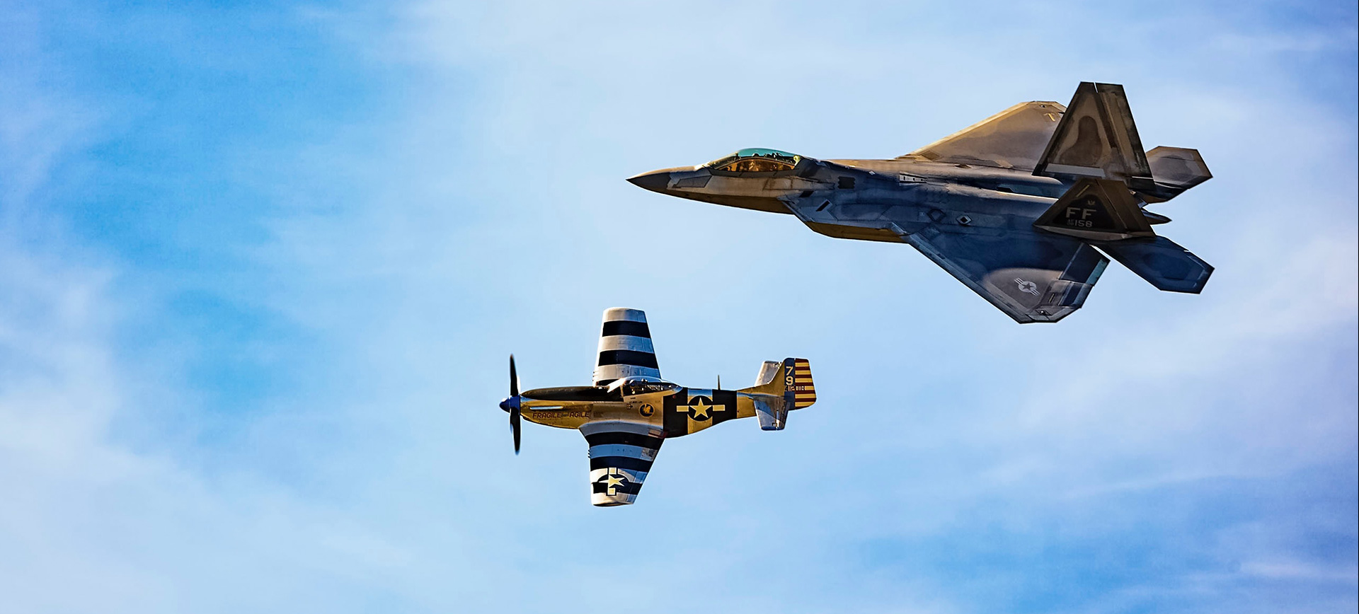 A fighter jet flying next to an airplane.